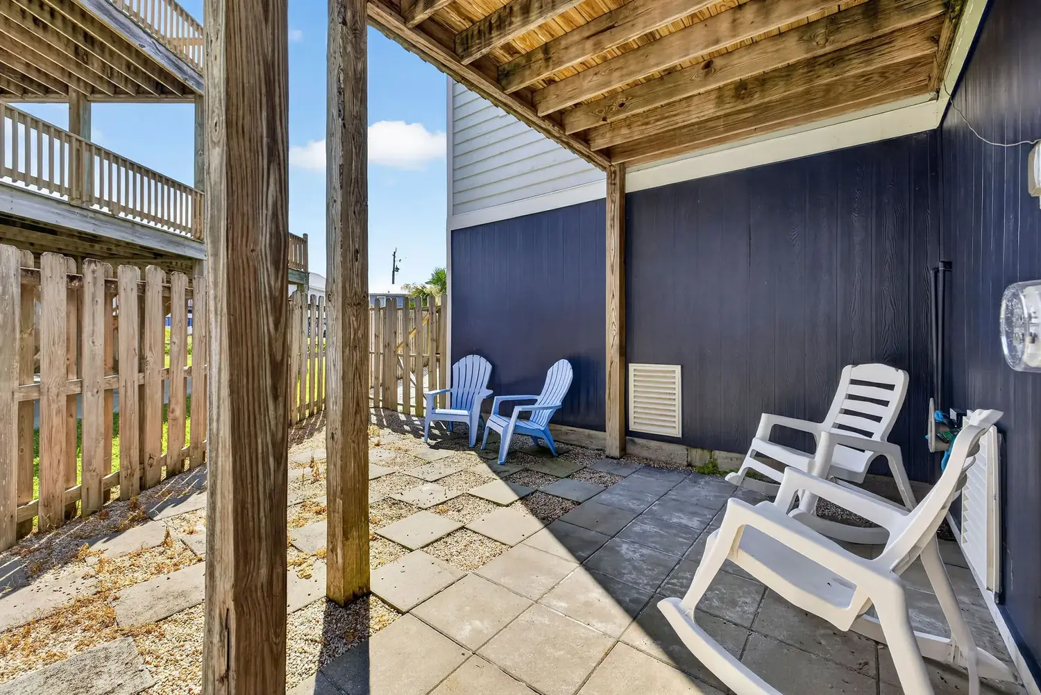 Private fenced courtyard with patio chairs beneath the deck