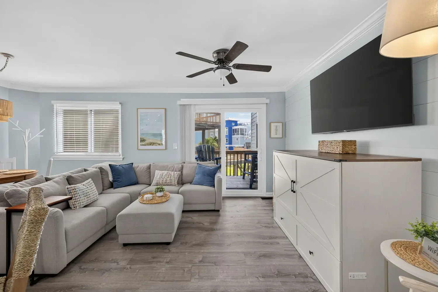 Living room with sectional sofa, coastal art, and sliding doors to the deck